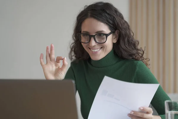Sonriente empleada italiana sosteniendo informe financiero y mostrando un gesto aceptable durante la videollamada —  Fotos de Stock