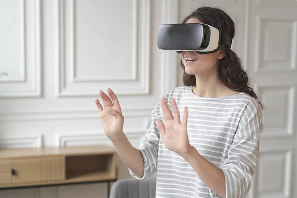 Joven mujer de negocios morena impresionada interactuando con la realidad virtual con gafas de realidad virtual — Foto de Stock
