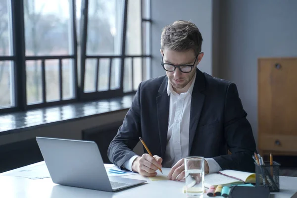Focado banqueiro masculino escreve memorandos em notas pegajosas enquanto trabalhava remotamente a partir de home office — Fotografia de Stock