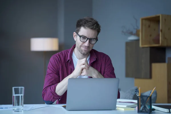Pensive jeune homme allemand employé de bureau à domicile est assis au bureau sur le lieu de travail fonctionne en ligne sur ordinateur portable — Photo