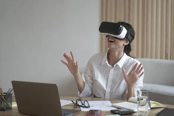 Mujer de negocios lleva auriculares VR para portátil levantando las manos como tratando de tocar objetos en la realidad 3D — Foto de Stock