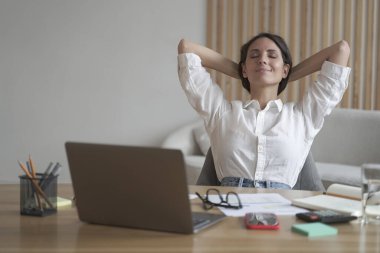 Genç mutlu İtalyan kadın ellerini başının arkasına koyup iş yerinde dinleniyor.