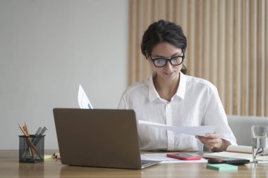 Resmi olarak odaklanmış genç İtalyan iş kadını belgeleri analiz ediyor, proje istatistiklerini okuyor