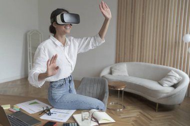 VR kulaklıklı iş kadını modern ofiste çalışırken üç boyutlu nesnelere dokunuyor.