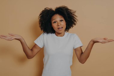 Belirsiz koyu tenli, omuzlarını silken ve kollarını yana doğru açan kadının stüdyo portresi soruya cevap veremiyor ya da bej arka planda tek başına dururken şüphe duymuyor.