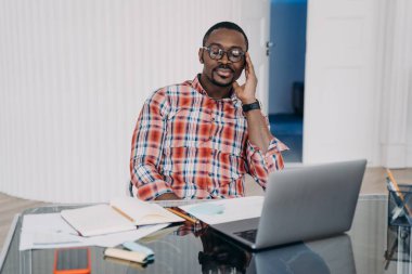 Tired african american male worker with closed eyes hold head with hand relax, have a break at workplace. Pensive black man at laptop collect thoughts together before work to increase productivity.