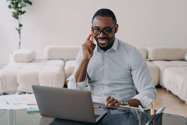 Smiling African American Businessman Talking Phone Looking Laptop Office Desk — Zdjęcie stockowe
