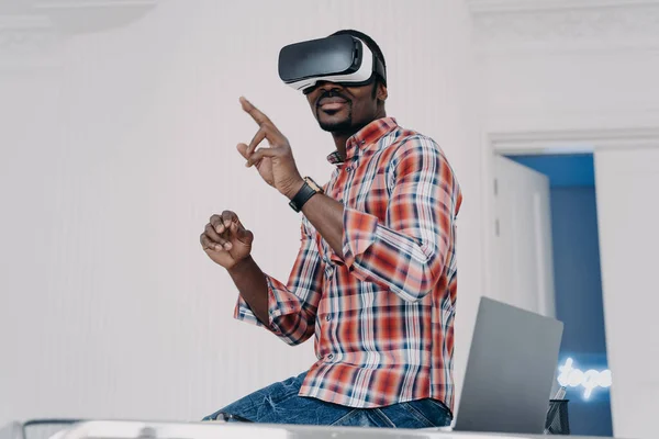 Interactive virtual reality goggles. African student in vr glasses at home office. Freelancer is working on design project. Digital technology for business and e-learning. Virtual distant study.