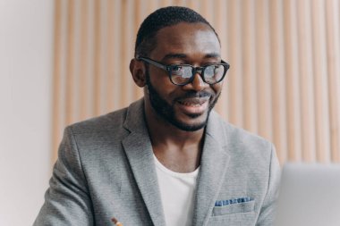 Resmi olarak kendine güvenen genç Afrikalı iş adamının portresi ofiste dizüstü bilgisayarın önünde oturmuş bilgisayar ekranına bakıyor, internette sörf yapıyor. Çeşitli iş insanları kavramı