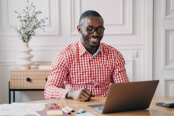 Młody Szczęśliwy Afrykański Pracownik Biura Czatujący Online Partnerem Biznesowym Podczas — Zdjęcie stockowe