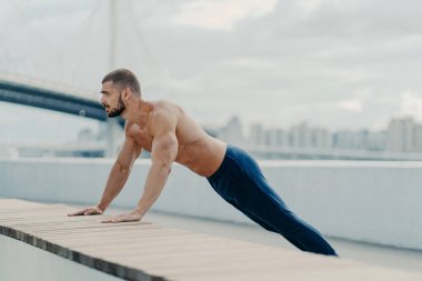 Atletizm sporcusu tahta duruşunda durur. Egzersiz yapar. Açık havada nefes alır. Temiz hava alır. Spor eğitimi konsepti