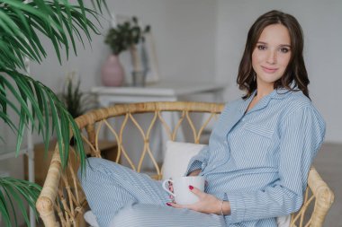 Güzel rahat Genç beyaz bir kadın rahat kıyafetler giymiş, içecekler sıcak çay veya cappucino, pozlar iç arka planı kapalı, boş zamanları vardır. Kişi, yaşam tarzı ve güzellik kavramı