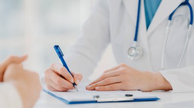 Tanımlanamayan kadın doktor panoya yazıyor, hasta için reçete yazıyor, analiz için veri kaydediyor, beyaz önlük giyiyor. Yaklaş, ellere odaklan. İlaç, sigorta, sağlık hizmeti kavramı