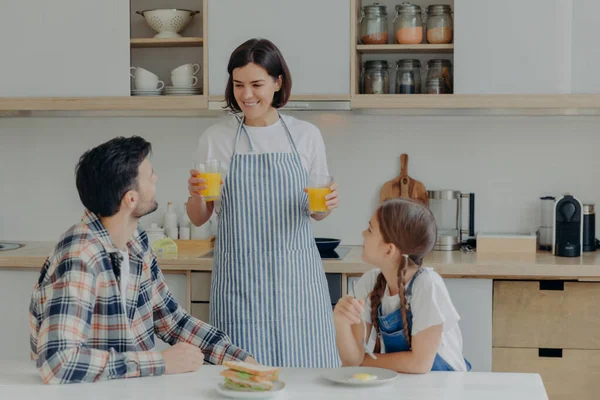 Lovely Happy Mother Wears Apron Holds Two Glasses Orange Juice — Foto Stock