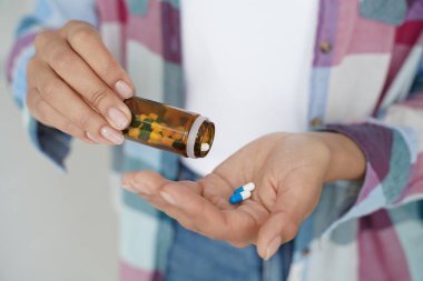 Close-up woman's hands holding pills and medicine jar. Female takes remedy, medication, painkillers, dietary supplement or vitamins. Modern pharmacy for body and mental health.