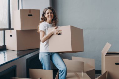 Happy home owner. European girl carrying box. Hispanic woman unpacking boxes. New apartment, mortgage and independence concept. Real estate advertising mockup.