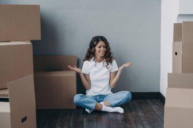 Nervous european woman has to pack the boxes. Girl is upset with moving. Annoyed young lady in jeans and white t-shirt is going to relocate. Homeowner getting stress from moving concept.