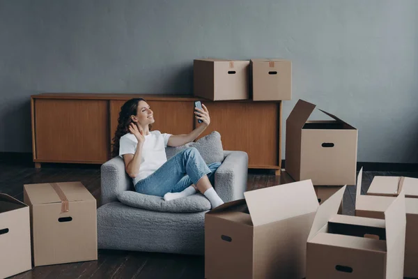Excited girl having video call on phone in new apartment. Successful independent young woman. Mover shows her dream house. Mortgage loan and happy home owner concept.