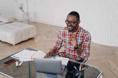 Teacher is speaking to student and shows ok gesture. Positive afro man has online conference on pc. Businessman is talking to client. Remote study, distance learning. Online tutor at work.