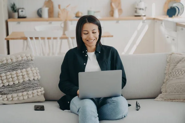 Усміхнена Молода Жінка Вчиться Ноутбуці Сидячи Дивані Вдома Купуючи Або — стокове фото
