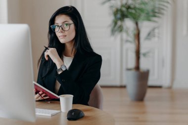 Ciddi bir kadının resmi deftere bilgi yazar, yeni online iş kursları öğrenir, bilgisayarla birlikte poz verir, proje üzerinde çalışır, bazı fikirler yazar. İş ve iş kavramı
