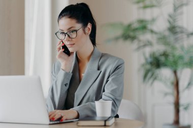 Ciddi esmer kadın klavye bilgisi, dizüstü bilgisayara odaklanmış, resmi kıyafetler giymiş, ortak çalışma alanında poz veriyor, gündüz çalışma sürecinde uzaktan çalışıyor..