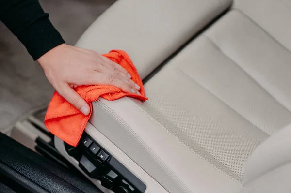 Close up shot of mans hand wipes car seat with microfiber cloth. Auto cleaning concept. Washing salon. Wiping dust