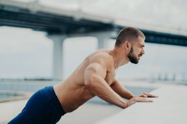 Güçlü kollu, kaslı, formda bir adamın yatay görüntüsü vücut egzersizlerini dışarı taşır, kalın sakalı vardır, mesafeye yoğunlaşır, düzenli olarak spora gider. Spor ve spor yaşam tarzı konsepti