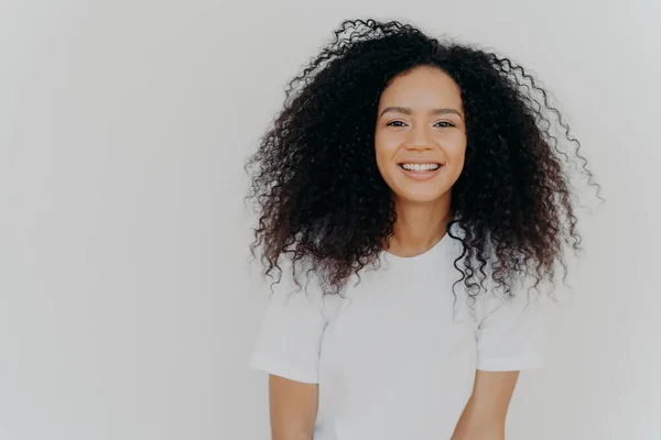 Headshot Souriant Woman Has Bushy Luminous Hair Stands Confident Pleased — Photo