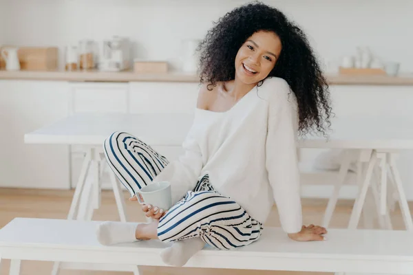 Pleased Young Girlfriend Afro Curly Hairstyle Sits Crossed Legs Bench — Stockfoto