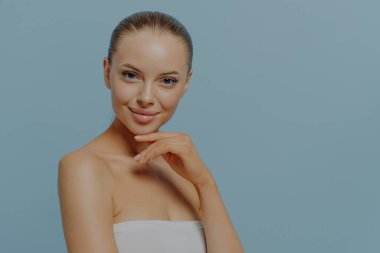 Web banner for skincare and dermatology clinic, female beauty portrait. Young sensual topless woman with healthy-looking clean skin smiling at camera, isolated on blue background, copy space for text