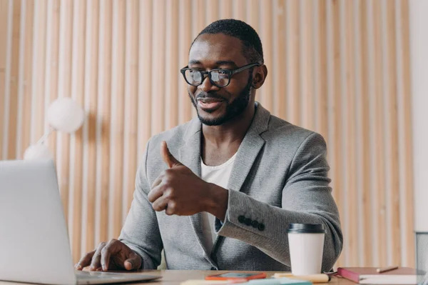 Happy Young African American Male Employee Glasses Talks Online Laptop — Zdjęcie stockowe