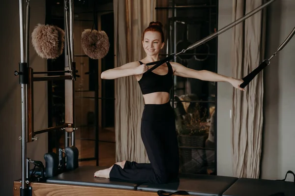 Wanita Jahe Yang Ceria Pada Pilates Reformer Melakukan Latihan Peregangan — Stok Foto