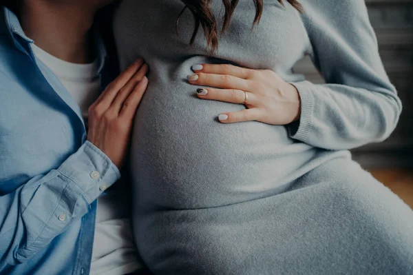 Face pregnant woman keeps hands on belly pose near husband await for child. Happy family concept. Pregnancy and parenthood concept