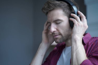 Gözü kapalı genç bir Alman 'ın fotoğrafında kulaklıkla müzik dinlerken neşeli bir yüz ifadesi, Avusturyalı adam evde boş vakit geçirirken favori müzik listesinin keyfini çıkarıyor.