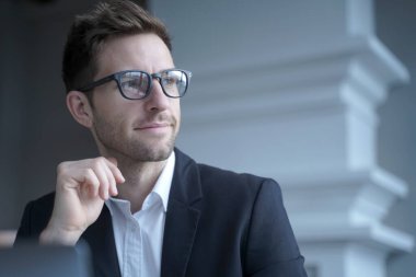 Resmi olarak kendine güvenen genç Avrupalı iş adamının portresi merkez ofisteki dizüstü bilgisayarın önünde oturmuş, düşünceli bir yüz ifadesiyle yan yana bakıyor. İş adamları konsepti