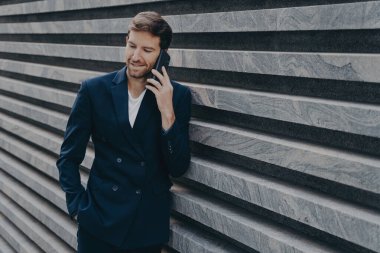 Başarılı erkek avukat, partneriyle istişarede bulunuyor. Siyah takım elbise cebinde. Akıllı telefon ile toplantı ayarlıyor. İnsan ticareti ve teknoloji kavramı