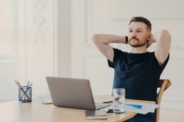 Mola verdim. Rahat poz veren, sıradan kıyafetler giyen, video izleyen ya da ev ya da modern ofis ortamından çalışırken dizüstü bilgisayardan bilgi okuyan serbest çalışan erkek ya da girişimci
