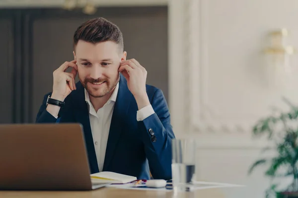 オフィスのデスクでノートパソコンの前に座っている間 従業員とオンライン会議を持つ正式な青いスーツを着て笑顔の経営者のビジネスマン — ストック写真