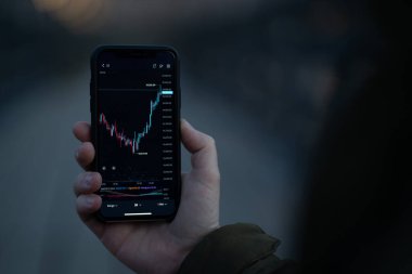 Eski ticaret. Ekranda şamdan çizelgesi olan erkek el bilgisayarı, finans haberleri okuyan tüccar ve açık havada dolaşırken mobil uygulamalarda gerçek zamanlı döviz piyasası verilerini kontrol ediyor