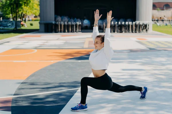 Flexible Fit Sportswoman Does Sport Exercises Outdoors Keeps Arms Raised — Photo