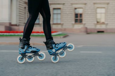 Mavi patenli tanınmayan bir kadın yola çıkıyor boş zamanlarını yolda geçiriyor yeni egzersizler deniyor eski binanın yakınında açık havada eğitim pozları veriyor. Hobi olarak paten kaymak. Etkin yaşam biçimi