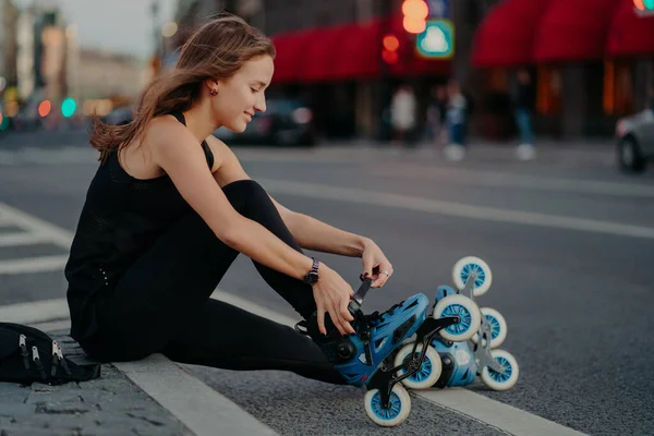 Outdoor Shot Active Woman Laces Rollerblades Prepares Ride Sits Road — Stok fotoğraf
