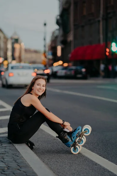 Outdoor Shot Active Slim Woman Poses Asphalt Puts Rollerskates Being — Fotografia de Stock