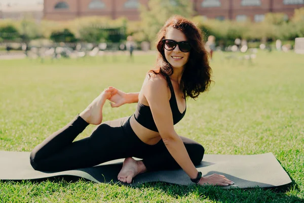 Outdoor Shot Sporty Smiling Woman Stretches Legs Karemat Smiles Positively — Stock Photo, Image