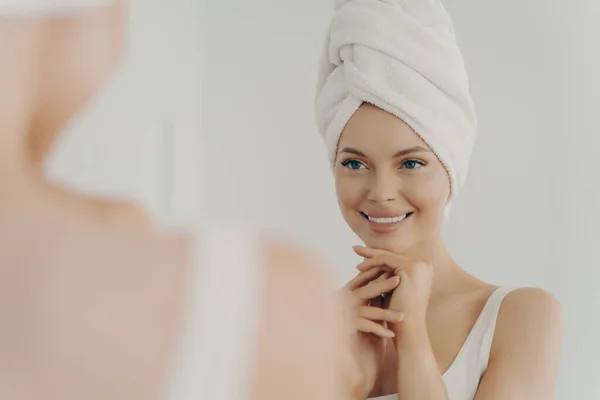 积极健康的年轻女性微笑着在镜子中使用面霜时 快乐迷人的女士在浴室日常美容美发中加入保湿滋养霜 — 图库照片