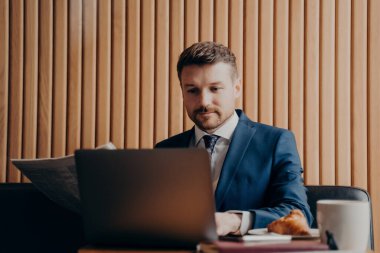 Resmi takım elbiseli, düzgün sakallı yakışıklı finansör. Laptop okuyor, gazete okuyor, kafede oturup kahve içiyor. Mola sırasında birden fazla iş yapıyor ve uzaktan kumandalı iş yapıyor.