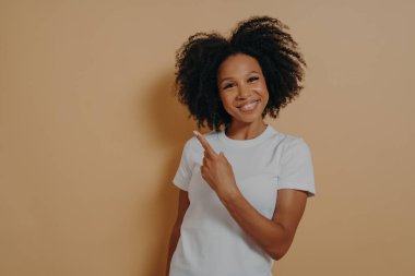 Beyaz gömlekli Afro model, boş fotokopi alanında işaret parmağı olduğunu ve sağ üst köşeyi göstererek gülümsediğini gösteriyor. Reklam ve tanıtım konsepti