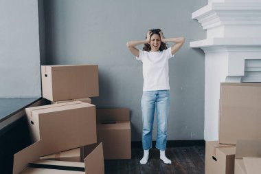 Tired overworked woman holding her head screaming standing with boxes feels panic due to long hard relocation, lost home, having problem with dwelling and money. Financial trouble, divorce, eviction.