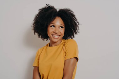 Stüdyo, afro-amerikan bir kızın komik bir yüz ifadesiyle rastgele giyinmiş portresini yakından çekti. Beyaz arka planda güzel kıvırcık saçlı, duygusal, genç, melez bir kadın.